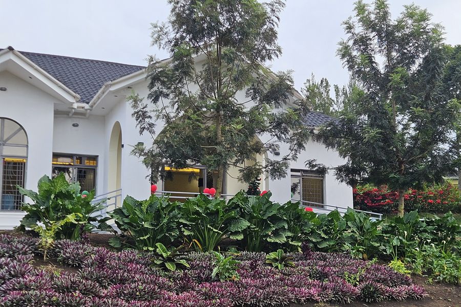 The white conference hall at Kaije with arched windows behind flower beds
