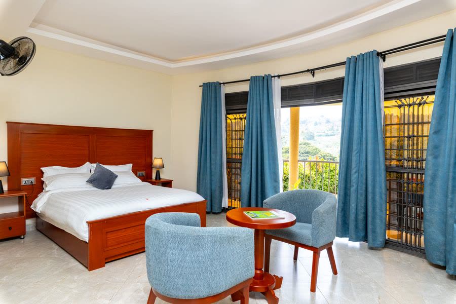 Cottage bedroom with a double bed, blue armchairs and doors onto the balcony