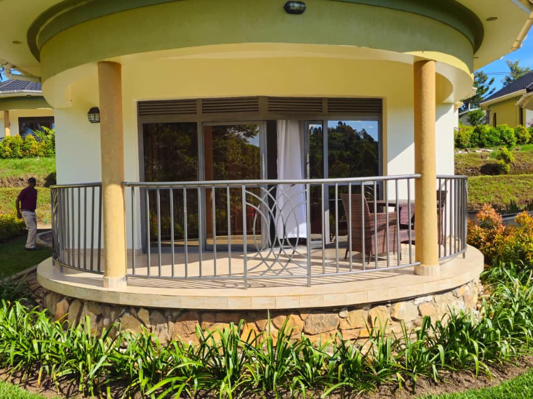 A cottage veranda with its curved iron railing above the flower beds