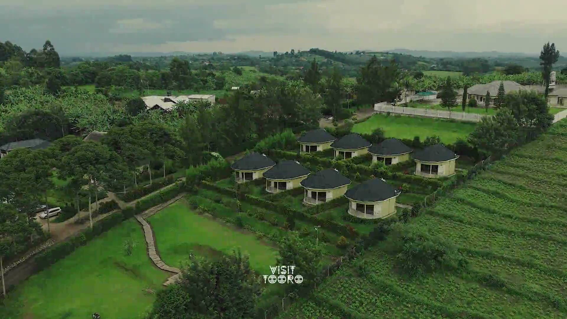 An aerial view over green hills to the cottages at Kaije