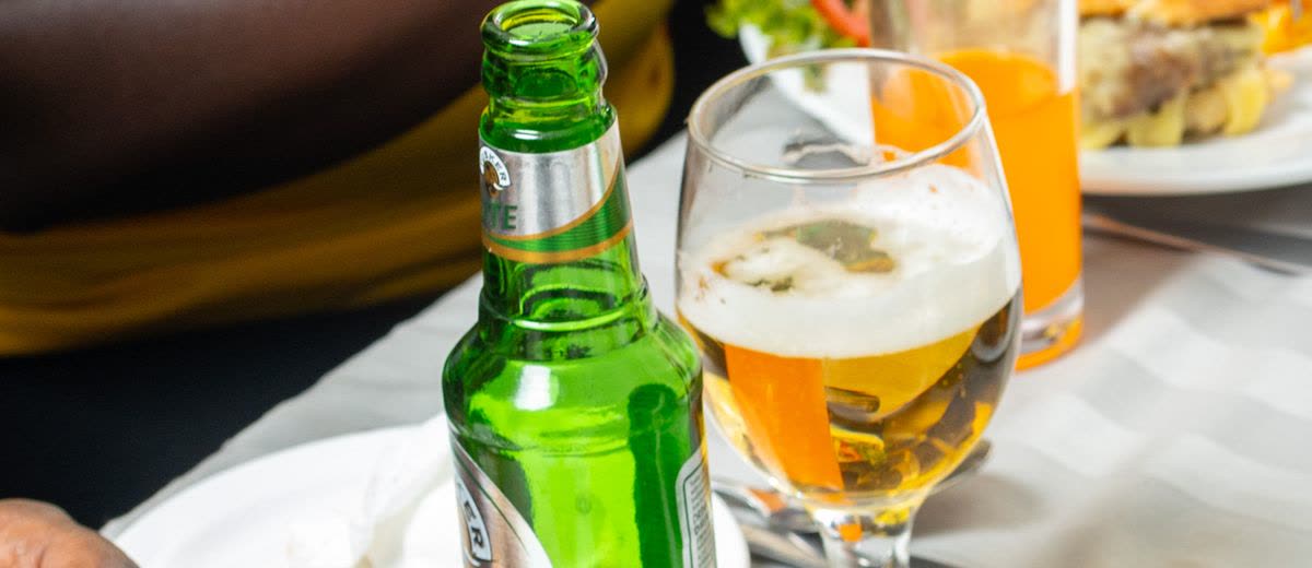A glass of beer poured beside a green bottle