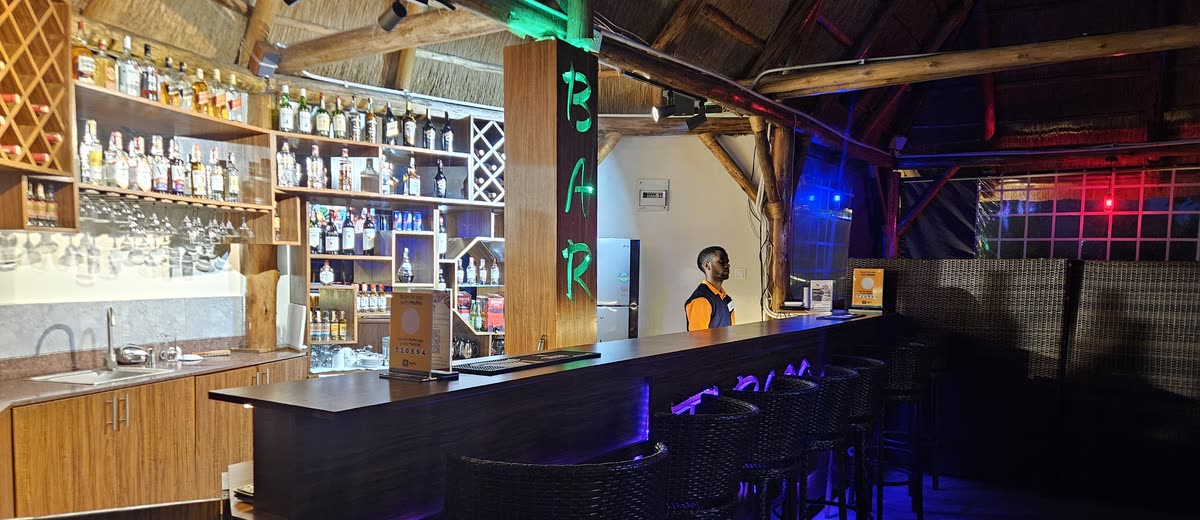 Turaco Bar at night, lit up under the thatched roof