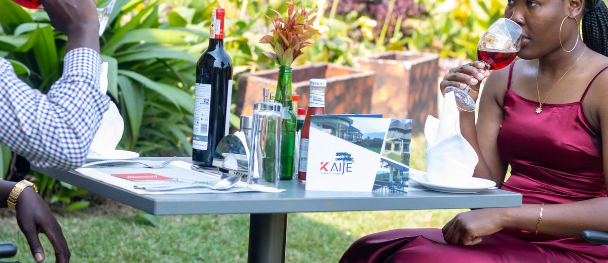 Two guests sharing red wine at a garden table
