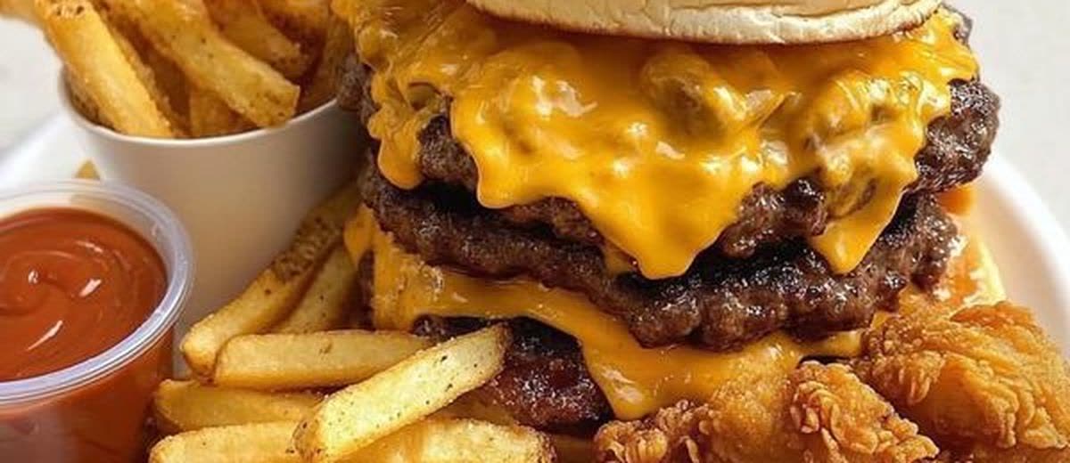 A double cheeseburger with fries and a dipping sauce