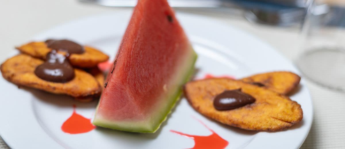 A watermelon wedge with fried plantain and chocolate sauce
