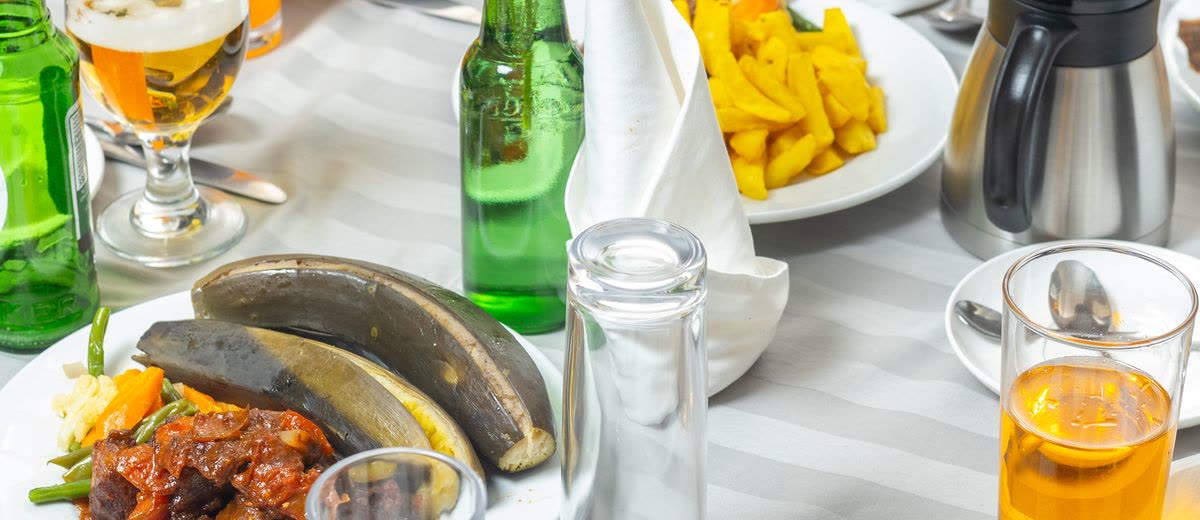 A stew with plantain, served with a cold beer and fresh juice