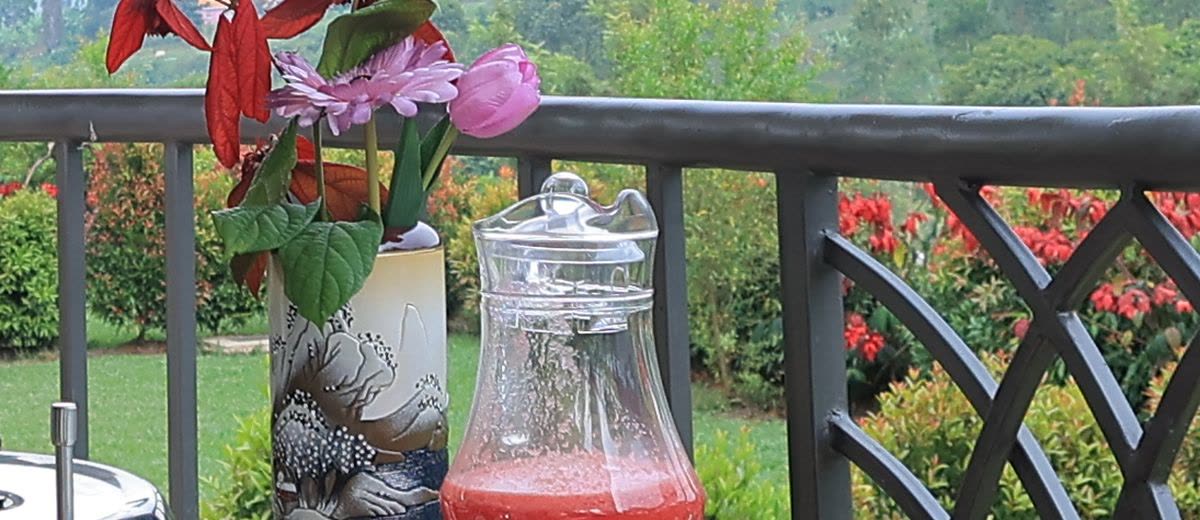 A jug of fresh juice on the terrace, with flowers and the garden beyond