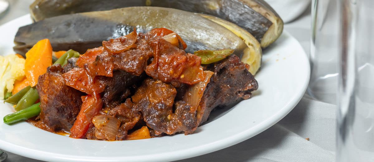 Beef stew with vegetables and plantain on a white plate