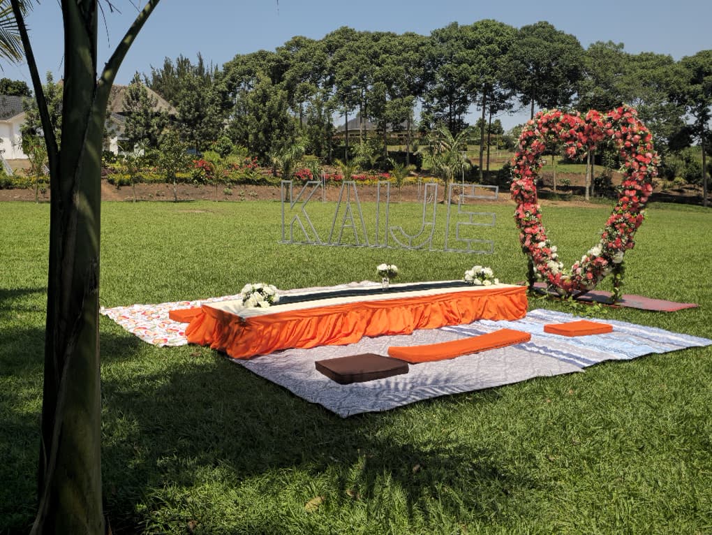 A low picnic table and cushions on the lawn beside a flower heart arch