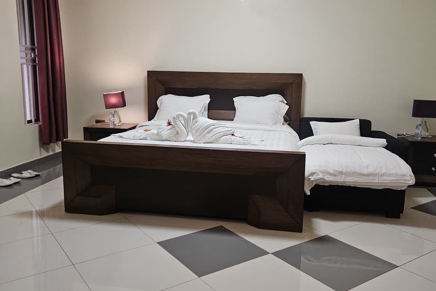 A villa bedroom with a dark wood bed and checked tile floor
