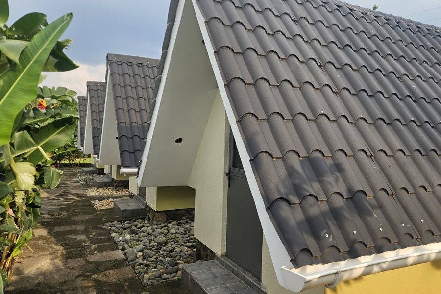 The tiled roof of an A-frame studio beside the garden