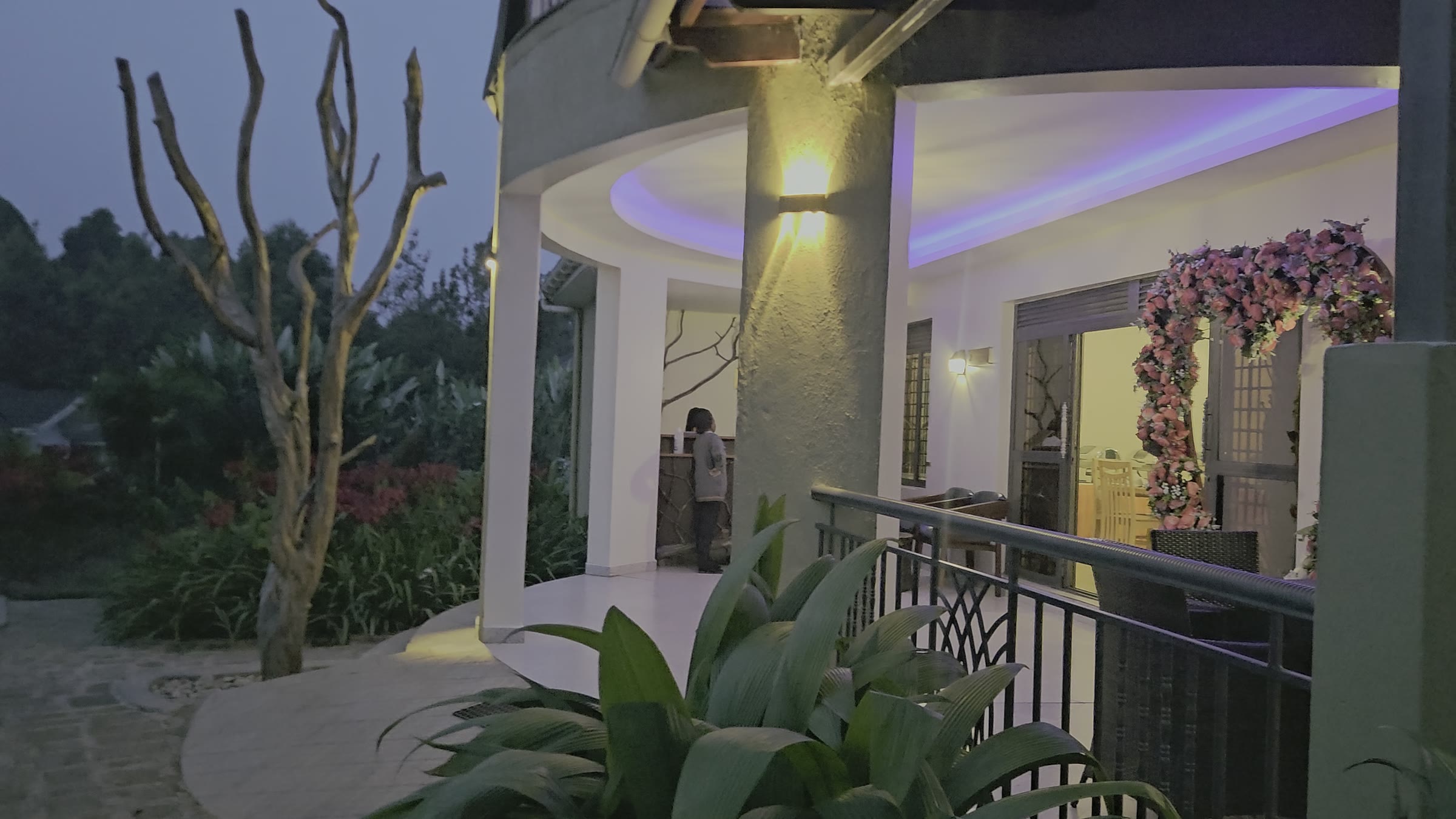 The curved restaurant terrace at dusk with soft ceiling lights and a flower arch