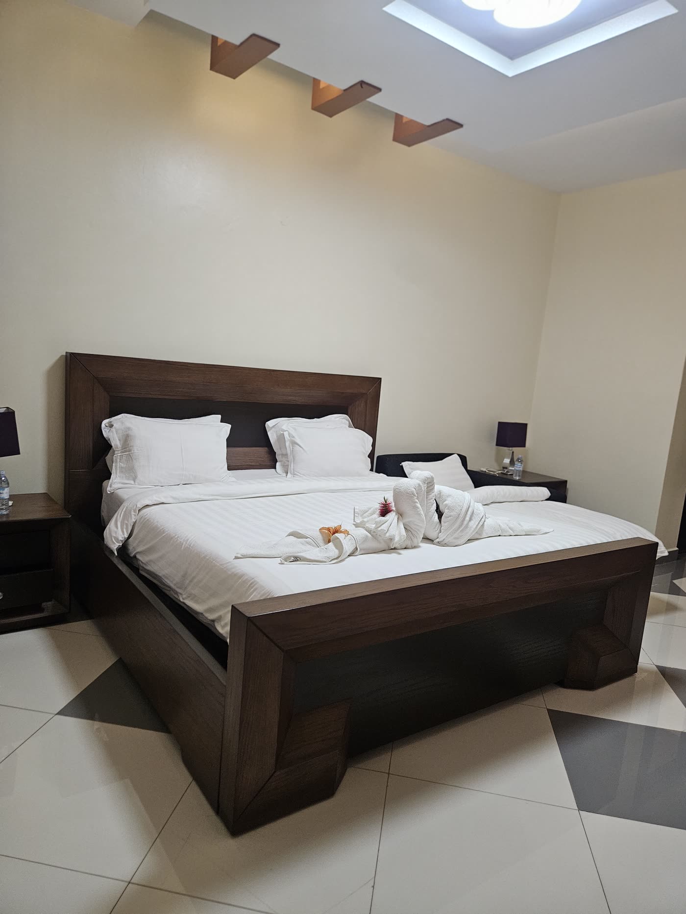 A dark wood double bed with folded towels