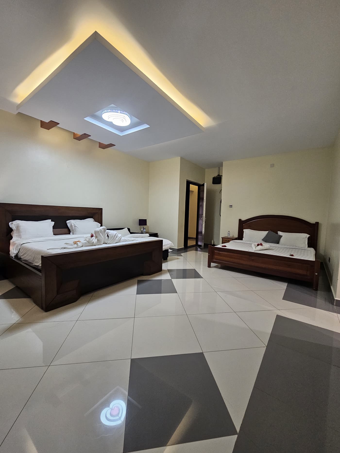 A large bedroom with two beds and a lit ceiling