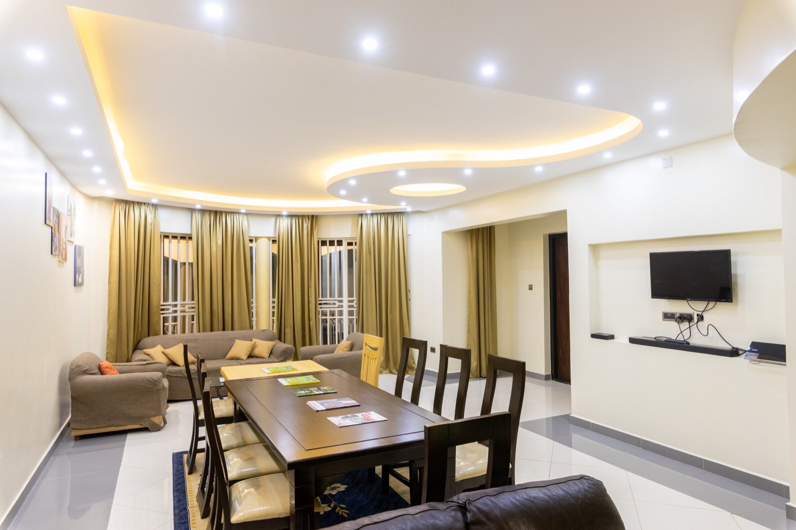 The villa living and dining room with a long table, sofas and a lit curved ceiling