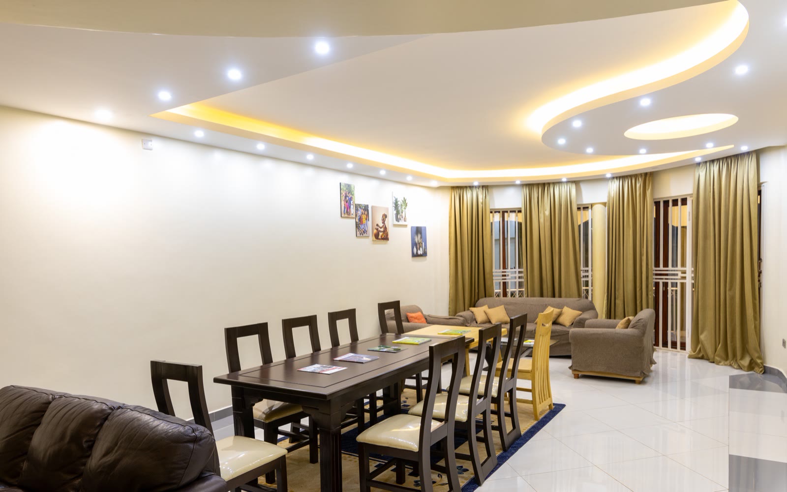 The villa lounge with sofas, a dining table and tall curtained windows