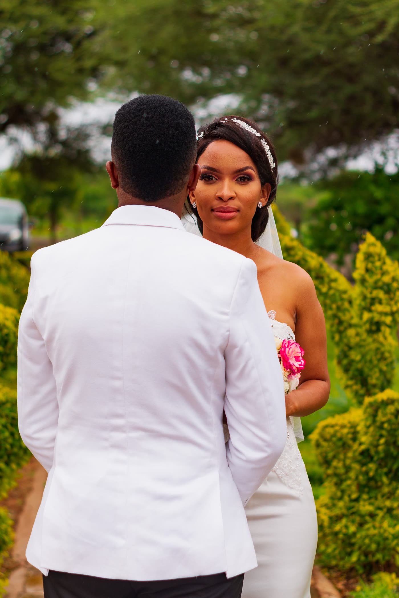 A bride and groom among clipped hedges in a garden